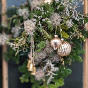 A festive door swag made from evergreen branches and hanging on a wooden door