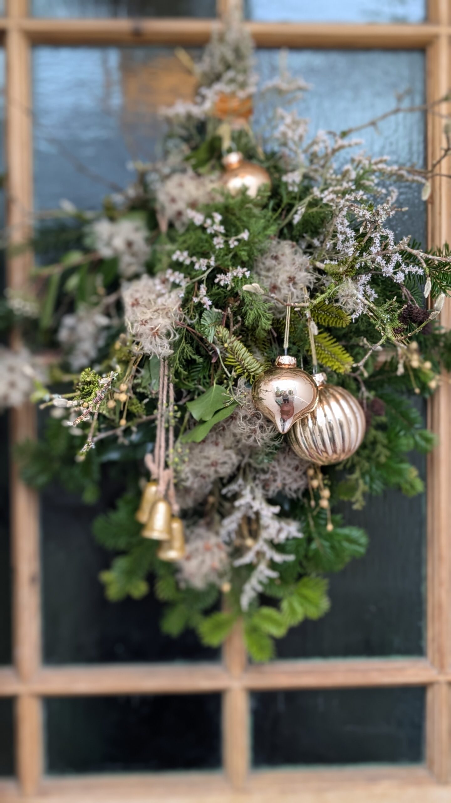 A festive door swag made from evergreen branches and hanging on a wooden door